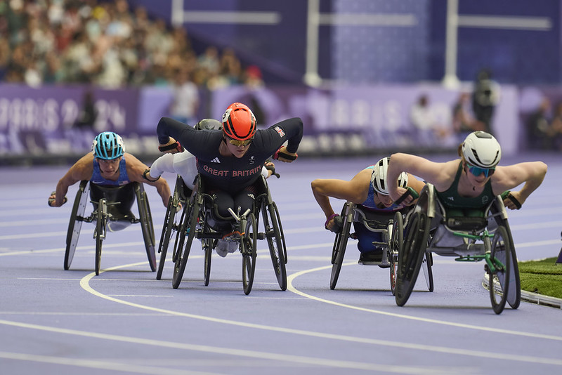 Eden racing in her wheelchair towards the camera with her competitors beside her 